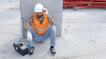 StokBuilder repairman, foreman in safety helmet and vest sitting down to rest at workplace in building next to tool box and ruler video
