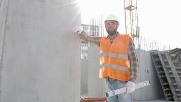 Builder repairman, foreman in safety helmet and vest works at his workplace in a building under construction video