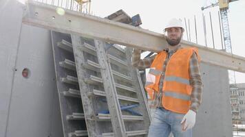 Builder man in hardhat and vest carrying timber on building site in his working day video