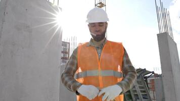 Builder repairman, foreman in protective helmet and vest stands at workplace in building and holds ruler in hands video