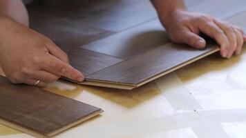 Close-up of a man kneeling and installing laminate flooring in a home. video