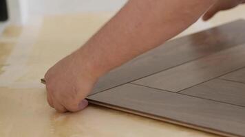 Close-up of a man kneeling and installing laminate flooring in a home. video