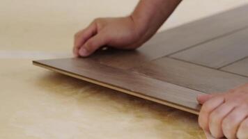Close-up of a man kneeling and installing laminate flooring in a home. video