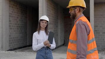 Construction workers inspecting building site progress, architect and foreman discussing project video