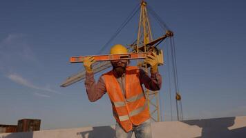 Construction worker using spirit level at building site with crane in background video