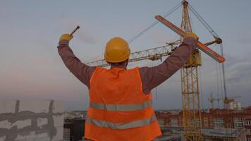 Construction worker celebrating with level and hammer at building site video