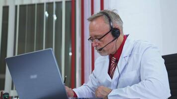 Man Having Call With Patient. Doctor with headset gives online consultation using laptop video