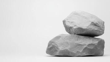 Two large gray rocks stacked on plain background, creating minimalistic and natural texture photo