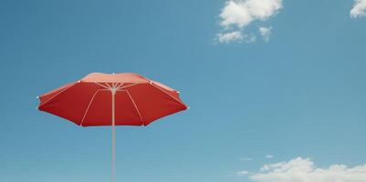 red beach umbrella under clear blue sky with scattered clouds photo