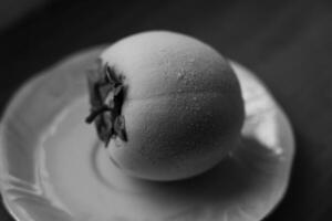 Frozen persimmon on a saucer. Persimmon covered with frost photo