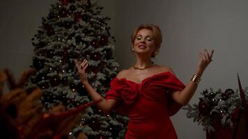 Beautiful singer performs in red dress, surrounded by Christmas decorations. She sings song about new year, while starring in music . video
