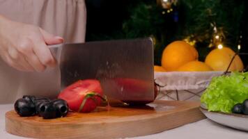 with strong and powerful spectacular movement, cook cuts juicy, wet, washed tomato of bright red color lying on a cutting board in half with a large knife. Slow motion video