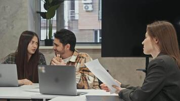 Young man and woman are openly flirting while sitting in office, which greatly annoys and irritates their colleague, who is trying to work. video