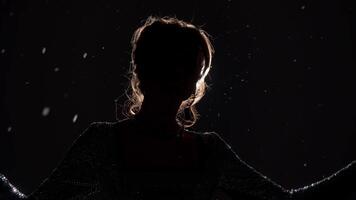 The singer performs New Year and Christmas songs on an abstract background during a snowy scene. Contre-jour video