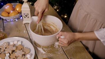 The cook mixes flour, eggs, and cream in a bowl using a whisk to create a dough for baking cakes and Christmas cookies. High angle. video