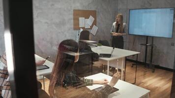 Students study in a modern, transparent lecture hall. They listen to the lecture and raise their hands, hoping to ask the teacher a question. video