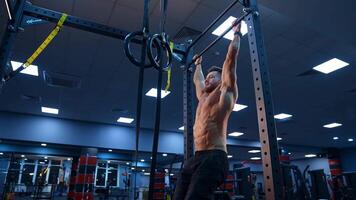 Bodybuilder exercising on horizontal bar. Shirtless man pulling up on horizontal bar in gym video