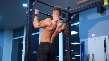 Man doing exersices on horizontal bar. Athlete muscular fitness male model pulling up on horizontal bar in gym video