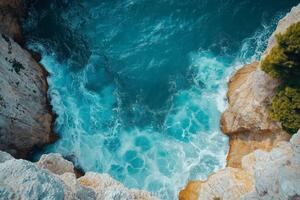 Turquoise sea crashing on rocky cliffs aerial view of dramatic coastal landscape photo