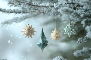 Delicate origami ornaments hanging on snowy christmas tree branch photo
