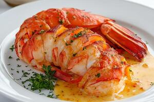 Grilled lobster tails with butter sauce and parsley garnish on white plate photo