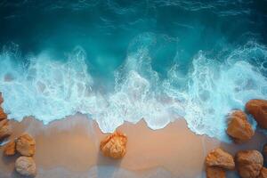 Turquoise ocean waves crashing on sandy beach with rocks, aerial view photo
