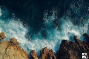 Ocean waves crashing on rocky coastline aerial view of turquoise water and rugged cliffs photo
