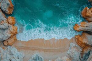 Turquoise water gently crashing on secluded sandy beach between rocks aerial view photo