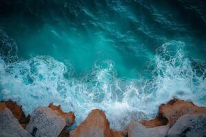 Turquoise water crashing on rocky coastline aerial view photo