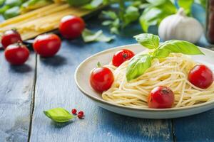 Delicious spaghetti with cherry tomatoes and basil on rustic blue table photo