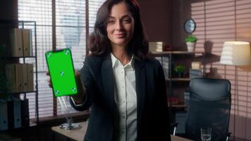 Caucasian woman showing mobile phone smartphone green screen chroma key space advertise smiling female girl businesswoman office indoor employee manager banker empty display web service ads business video