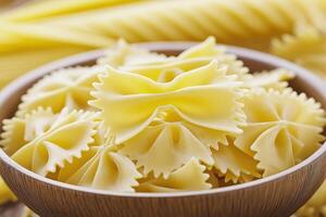 Farfalle pasta in wooden bowl with blurred background of more pasta photo
