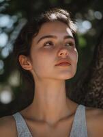 Young woman looking up, enjoying sunlight in nature photo