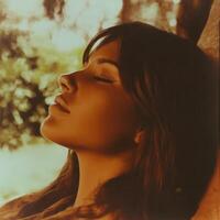 Beautiful young woman relaxing with eyes closed in warm sunlight photo