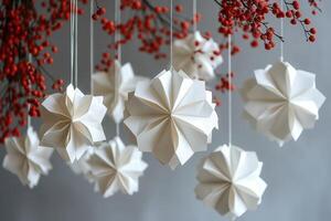 White origami paper christmas decorations hanging with red berries photo