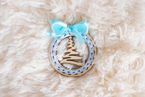 Christmas wooden decoration with ribbon on fluffy light background with copy photo
