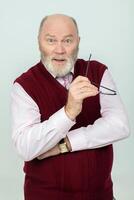An elderly gray-haired man with a beard looks at the camera in surprise. photo