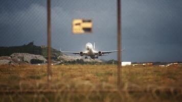 Airplane with an unrecognizable livery speed up before takeoff, view through the airport fence. Flight departure. Jet on the runway. Glowing runway. video