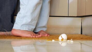 A childs tiny footsteps are seen next to a broken egg lying on the kitchen floor video