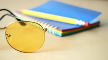 A collection of Stylish Sunglasses and a Colorful Notepad placed on Desk video
