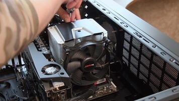 Male hands with screwdriver unassemble CPU cooler from motherboard with NVidia GeForce RTX graphics card installed inside gaming PC tower. Processor cooler fan assembling. Odessa, Ukraine, 04 04 2021 video