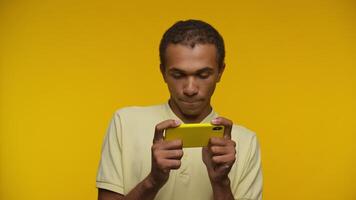 Man playing on a yellow smartphone on yellow background video