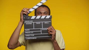 Young Filmmaker Holding a Clapperboard on Yellow Background video