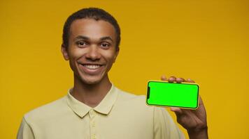 Smiling Man Holding Smartphone with Green Screen on Yellow video