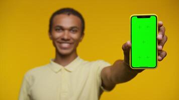 Man showing smartphone with green screen on yellow background video