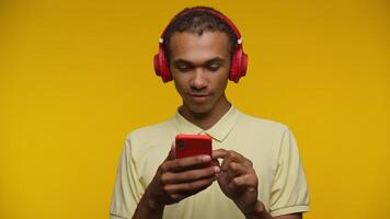 Smiling Man with Red Headphones Using Smartphone on Yellow Background video