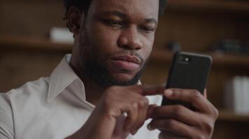 Rack focus from a smart phone to a man's portrait while browsing video