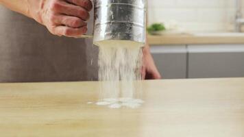 man holds a sieve in his hands and sifts flour. The cooking process. The cook starts pouring flour. video