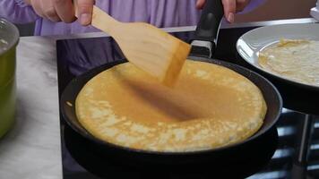 Cooking homemade pancakes on a stovetop with wooden spatula in a kitchen setting video
