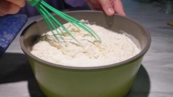 Mixing flour with a green whisk in a bowl. hands-on baking preparation video